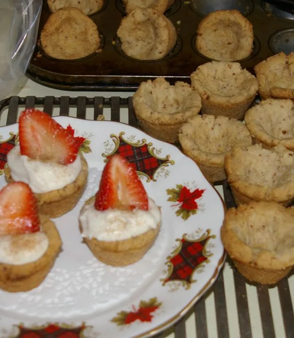 Baked tart shells filled with cream and strawberry slice.